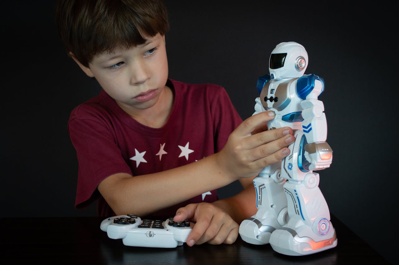 A young boy engages with a robot toy using a remote control against a black background.